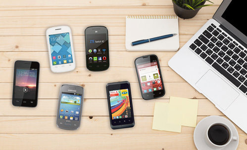 Different smartphones on a desk with a laptop and cup of coffee
