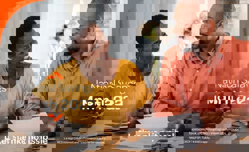 Smiling man and woman sitting at a table. woman writing in book, man holding documents