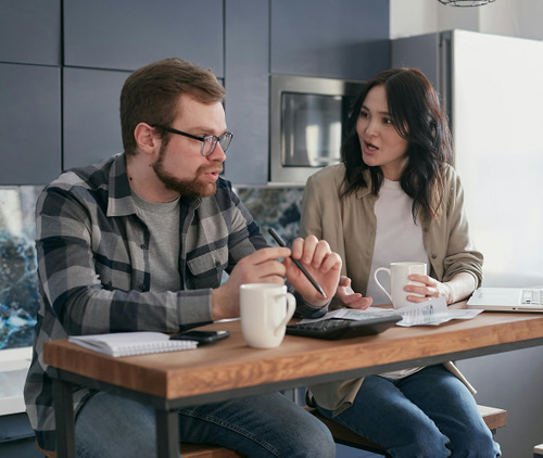 Couple working on financial planning with documents, a calculator, and coffee.