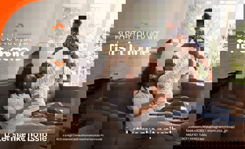 Laughing couple sitting on couch, lifting baby in the air, and boxes around tghem